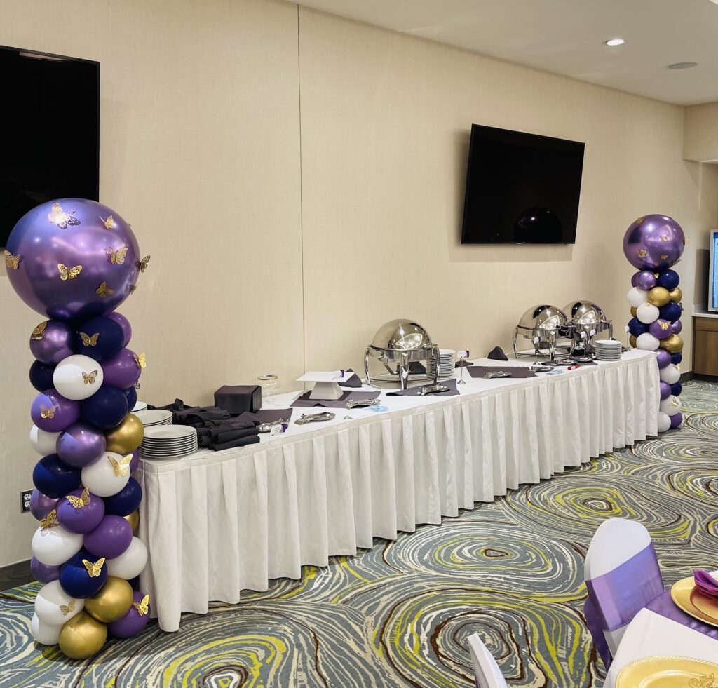 A buffet table with balloon columns on the ends.